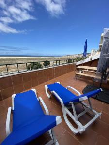 a pair of blue and white chairs on a balcony with the beach at Panorama Sun Figueira - 1er ligne Mer in Figueira da Foz