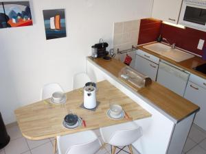 eine kleine Küche mit einem Holztisch und Stühlen in der Unterkunft Holiday Home Hameau des Tamarins-1 by Interhome in Le Barcarès
