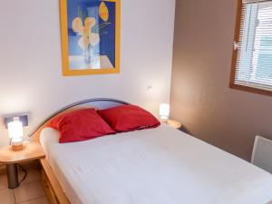 ein Bett mit zwei roten Kissen in einem Schlafzimmer in der Unterkunft Holiday Home Hameau des Tamarins-1 by Interhome in Le Barcarès