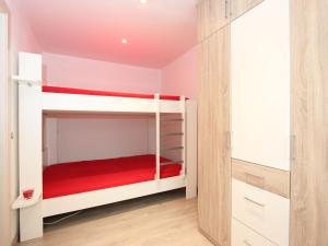 a small bedroom with two bunk beds with red sheets at Apartment Am Birkenhain-30 by Interhome in Seefeld in Tirol