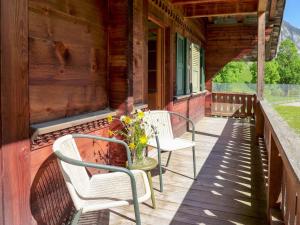 um alpendre com duas cadeiras e um vaso de flores em Apartment Chalet Alte Post by Interhome em Schwenden