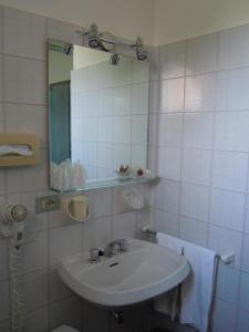 a white bathroom with a sink and a mirror at Albergo Bagner in Sirmione