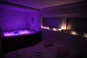 プラハにあるWellness Vila Bohemiaの紫色の照明付きのバスタブが備わる紫色の客室です。
