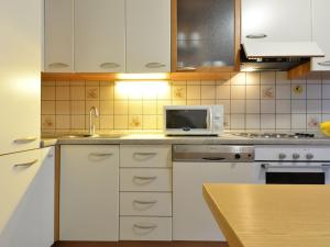 a kitchen with white cabinets and a microwave at Apartment Condominio al Parco-2 by Interhome in Canazei