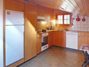 a kitchen with wooden cabinets and a white refrigerator at Apartment Armorial II - apt 6 by Interhome in Villars-sur-Ollon