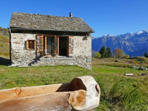 a log bench in front of a stone house at Holiday Home Rustico Andrea by Interhome in Acquarossa