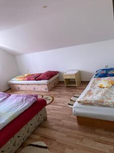 three beds in a room with wooden floors at Superubytovanie Olga in Štrba