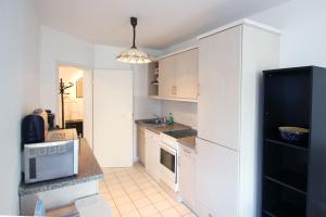 a kitchen with white cabinets and a black refrigerator at Ferienwohnung am Potenberg FeWo 6 - Balkon in Binz