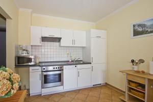 eine Küche mit weißen Schränken und einem Waschbecken in der Unterkunft Villa Laetitia FeWo 16 - strandnah, Balkon in Binz