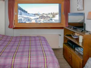 a bedroom with a bed and a tv and a window at Studio Rosablanche-106 by Interhome in Siviez
