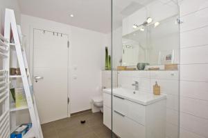 La salle de bains blanche est pourvue d'un lavabo et de toilettes. dans l'établissement Ostseeresort Binz Prora, à Binz
