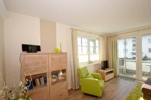 a living room with a green chair and a television at zentrumsnahe Ferienwohnung mit Balkon, gratis Nutzung vom AHOI Erlebnisbad und Sauna in Sellin, eigene Sauna - Villa Antje Whg 10 in Göhren