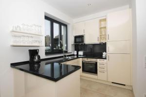 a kitchen with white cabinets and a black counter top at App Prora Solitaire FeWo 8 Balkon, Strand, Wellness in Binz