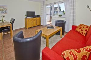 un salon avec un canapé rouge et une table dans l'établissement zentral aber ruhig, Balkon, gratis Nutzung vom AHOI Erlebnisbad und Sauna in Sellin - Villa Elisenhof FeWo 2, à Göhren