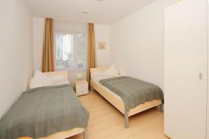 une chambre avec deux lits et une fenêtre dans l'établissement zentral aber ruhig, Balkon, gratis Nutzung vom AHOI Erlebnisbad und Sauna in Sellin - Villa Elisenhof FeWo 2, à Göhren 13 autres photos