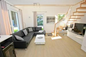 a living room with a black couch and a staircase at strandnahes Ferienhaus mit eigener Sauna und Kamin - Ferienhaus am Dünenstrand in Baabe