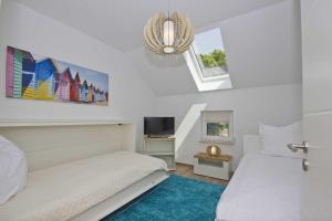 Habitación blanca con 2 camas y lámpara de araña. en FeWo Helligdom FeWo 04 - Balkon, Meerblick, en Breege