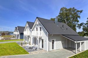 a white house with a black roof at Ferienhaus Mantje Mantje Haus - Meerblick, Sauna, Terrasse in Gager