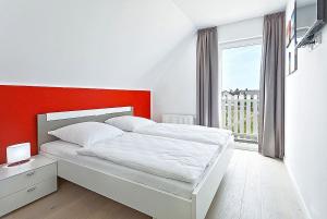a bedroom with a white bed with an orange wall at Ferienhaus Mantje Mantje Haus - Meerblick, Sauna, Terrasse in Gager