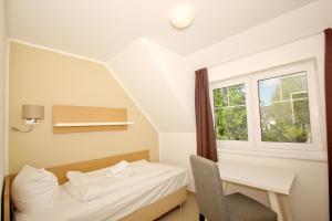 a room with a bed and a desk and a window at Strandresort Rex Rugia Ferienwohnung 14-6 mit Sauna- und Schwimmbadnutzung im AHOI Sellin in Lobbe +16 photos