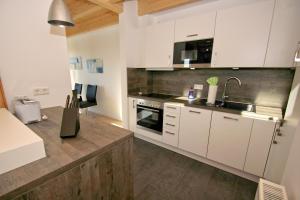 a kitchen with white cabinets and a sink at Ferienhaus TimpeTe Haus Backbord - Terrasse, Meerblick, Sauna in Gager