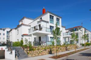 ein weißes Gebäude mit einem roten Kamin in der Unterkunft zentrale FeWo mit Balkon, gratis Nutzung vom AHOI Erlebnisbad und Sauna in Sellin - Villa Anni FeWo 05 in Göhren