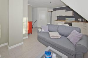 a living room with a gray couch and a kitchen at Ferienwohnung Liesi FeWo OG - Balkon, ruhige Lage in Putbus