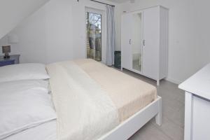a white bedroom with a bed and a mirror at Ferienwohnung Liesi FeWo OG - Balkon, ruhige Lage in Putbus