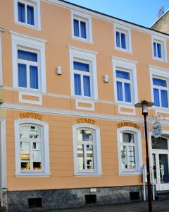ein orangefarbenes Gebäude mit weißen Fenstern und einem Straßenlicht in der Unterkunft Brocki's Hotel Stadt Hamburg in Parchim