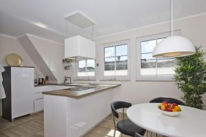 a kitchen with white cabinets and a table with a bowl of fruit at Ferienhaus Auszeit FeWo 03 - Dachterrasse, ruhige Lage in Middelhagen +12 photos