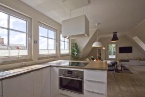 una cocina con armarios y ventanas blancos y una isla de cocina en Ferienhaus Auszeit FeWo 03 - Dachterrasse, ruhige Lage, en Middelhagen