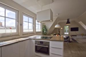 a kitchen with white cabinets and windows and a kitchen island at Ferienhaus Auszeit FeWo 03 - Dachterrasse, ruhige Lage in Middelhagen