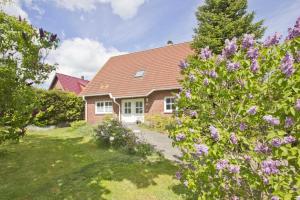 a brick house with purple flowers in the yard at Ferienhaus Gisela Gartenblick - Terrasse, Garten, Sauna in Putbus