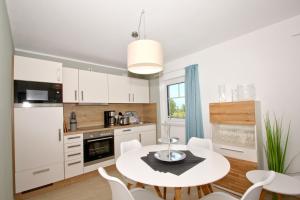 eine Küche mit einem weißen Tisch und weißen Stühlen in der Unterkunft strandnahe FeWo mit Balkon, gratis Nutzung vom AHOI Erlebnisbad und Sauna in Sellin - Rex Rugia FeWo 10-7 in Lobbe