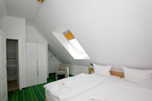 1 Schlafzimmer mit 2 weißen Betten und einem Dachfenster in der Unterkunft strandnahe FeWo mit Balkon, gratis Nutzung vom AHOI Erlebnisbad und Sauna in Sellin - Rex Rugia FeWo 30-6 in Lobbe + 17 Fotos