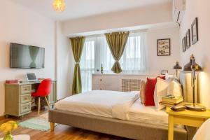 Dormitorio con cama, escritorio y TV en Piata Victoriei by MRG Apartments, en Bucarest