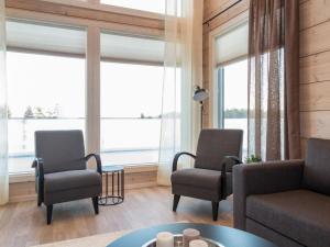 a living room with two chairs and a couch and windows at Holiday Home Viherlaakso a by Interhome in Tahkovuori