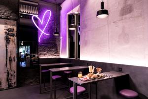 un restaurante con iluminación púrpura y 2 mesas y taburetes en Heart Hotel Milano en Milán