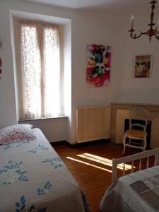 um quarto com uma cama, 2 janelas e uma cadeira em La Languedocienne appartement climatisé centre ville wifi inclus em Limoux