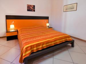 Una cama con colcha de color naranja en una habitación en Apartment Rosapanna-1 by Interhome, en Rosapineta