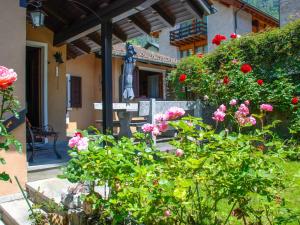a garden with pink flowers and a statue in front of a building at Holiday Home La Casina by Interhome in Olivone