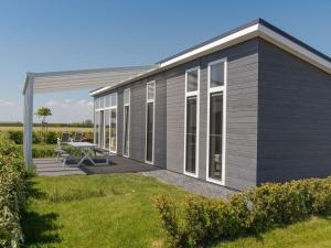 a modular home with a patio and grass at Holiday Home Water Resort Oosterschelde - nr- 47A by Interhome in Wemeldinge