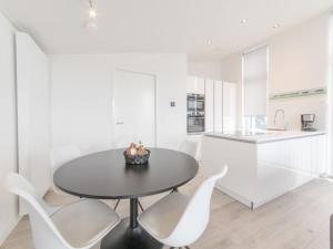 a kitchen and dining room with a black table and white chairs at Holiday Home Water Resort Oosterschelde - nr- 47A by Interhome in Wemeldinge