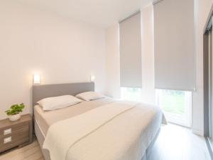 a white bedroom with a large bed and windows at Holiday Home Water Resort Oosterschelde - nr- 47A by Interhome in Wemeldinge