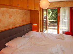 a bed in a room with a large window at Apartment Platanes A1 by Interhome in Nendaz