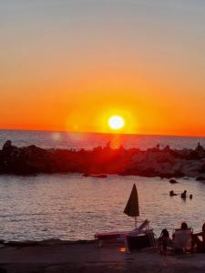 una puesta de sol en la playa con gente en el agua en Chalet 4 or 6 persons Toscana Viareggio Camping Bosco Verde Italië en Torre del Lago Puccini