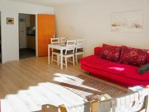 ein Wohnzimmer mit einem roten Sofa und einem Tisch in der Unterkunft Apartment Promenade - Utoring-92 by Interhome in Arosa