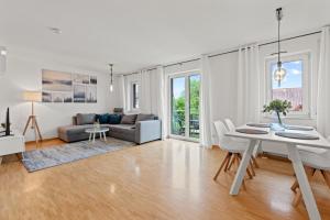 sala de estar blanca con mesa y sofá en TTP Apartment 6 Friedrichshafen, en Friedrichshafen