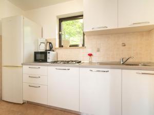 eine Küche mit weißen Schränken und einem weißen Kühlschrank in der Unterkunft Holiday Home Erminia by Interhome in Lovran