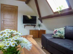 ein Wohnzimmer mit einem Sofa, einem TV und Blumen in der Unterkunft Apartment Storchennest by Interhome in Meißenheim